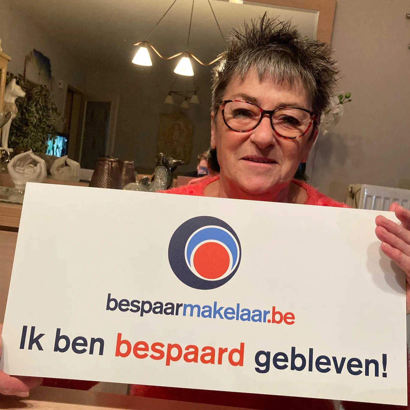 Klant met bril met het bordje 'Ik ben bespaard gebleven!'
