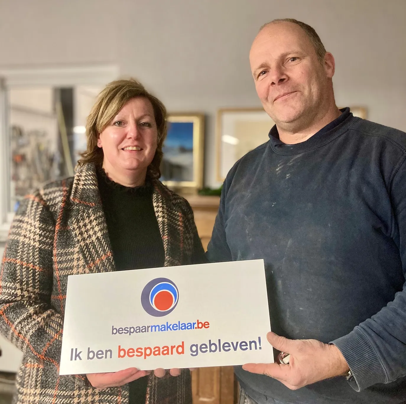 Twee klanten in hun zaak met het bordje 'Ik ben bespaard gebleven!'