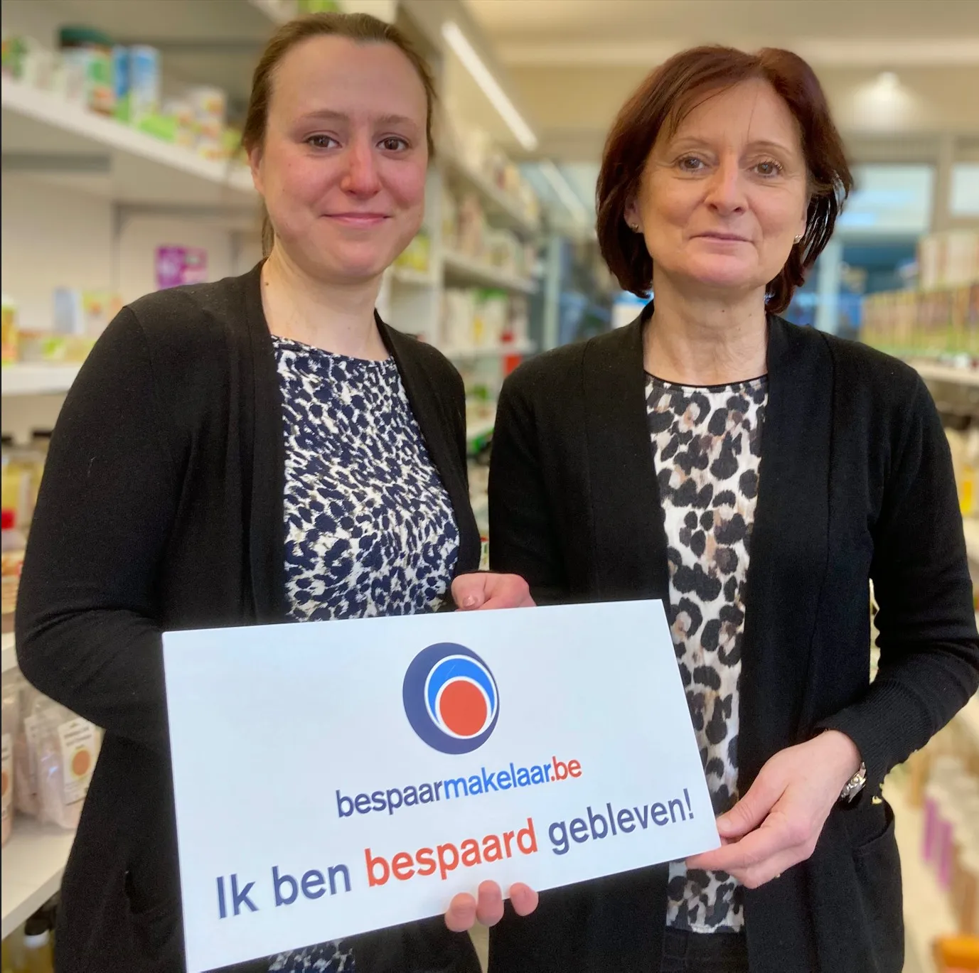 Twee vrouwen met het bordje 'Ik ben bespaard gebleven!'