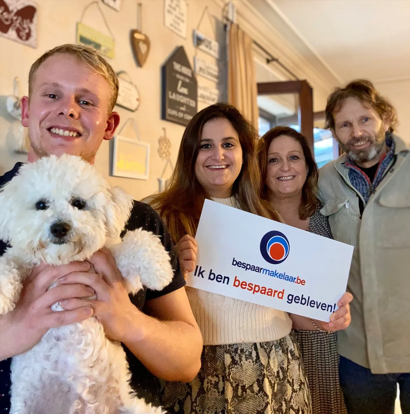 Groep klanten met een witte hond met het bordje 'Ik ben bespaard gebleven!'