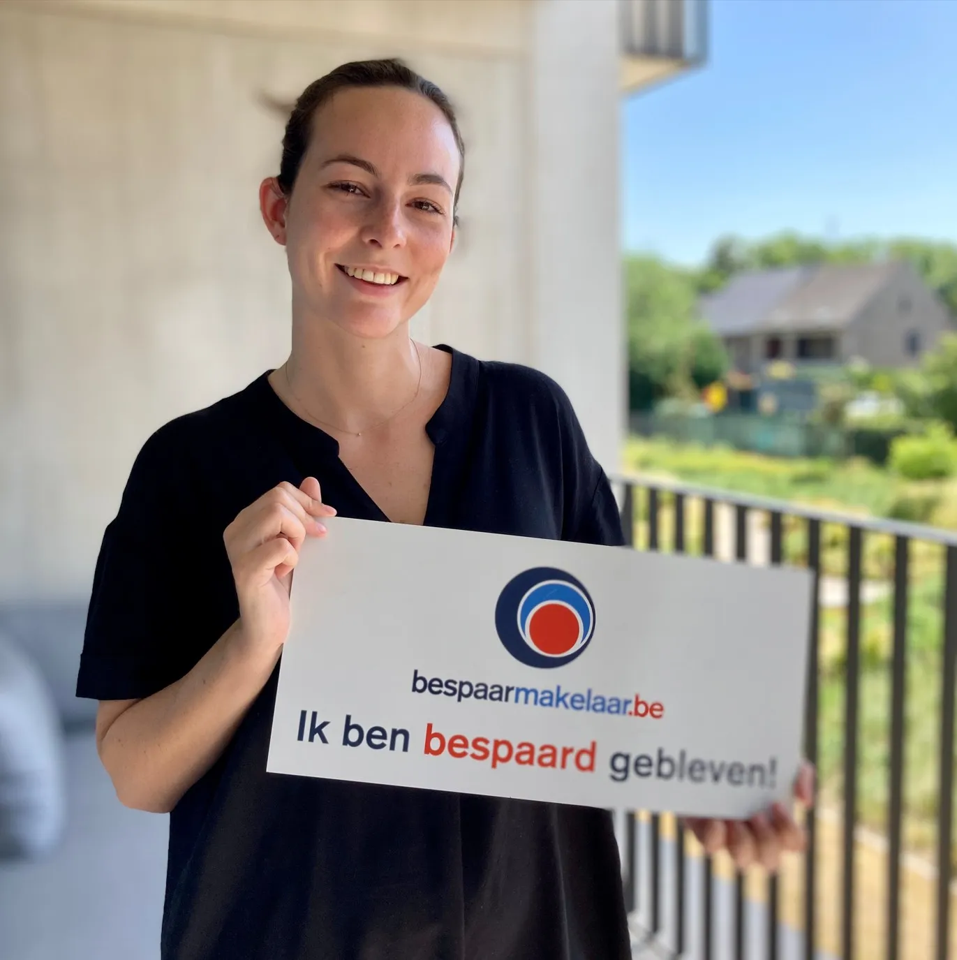 Vrouw op een terras met het bordje 'Ik ben bespaard gebleven!'